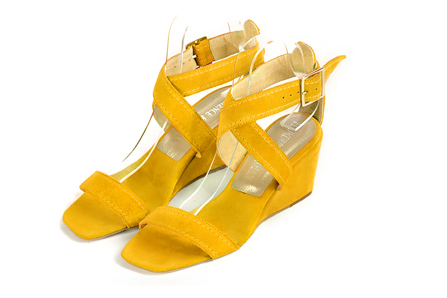 Yellow elegant sandals with cross straps across the instep, fully open. Square toe. Medium wedge heels.